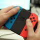 A person is holding the neon blue and red Joy-Con controller in their hands.
